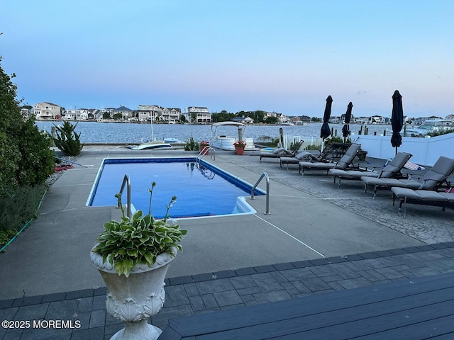 view of swimming pool featuring a patio and a water view