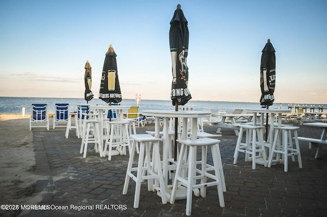 patio terrace at dusk with a beach view and a water view