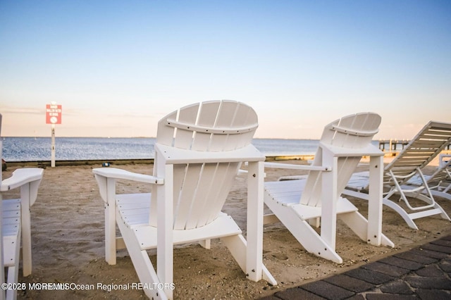 patio terrace at dusk with a water view and a beach view