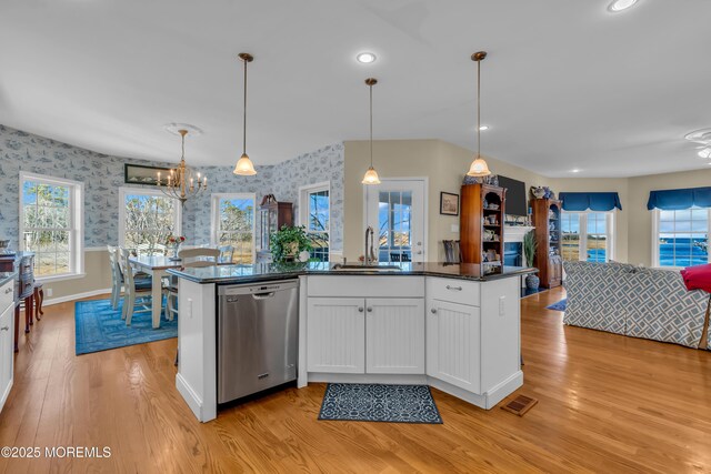 kitchen with pendant lighting, sink, light hardwood / wood-style flooring, white cabinetry, and stainless steel dishwasher