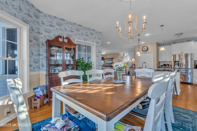 dining area with hardwood / wood-style floors and ceiling fan with notable chandelier