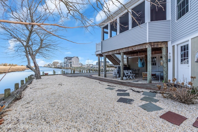 view of yard featuring a patio, a water view, and a sunroom