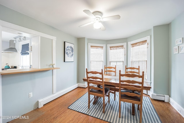 dining area with hardwood / wood-style flooring, a baseboard radiator, and ceiling fan