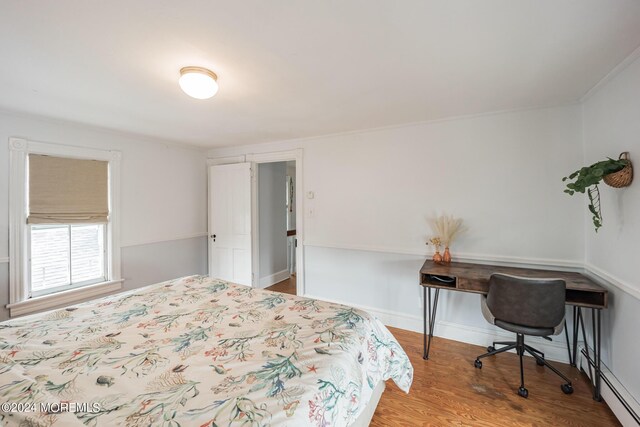 bedroom featuring a baseboard heating unit and wood-type flooring