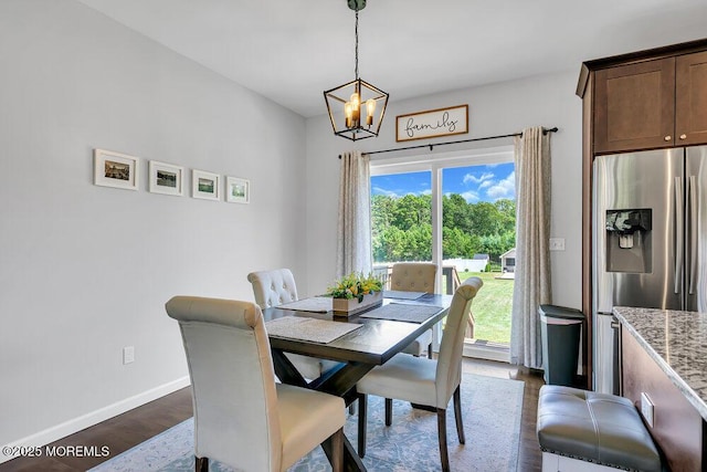 dining area with dark wood-type flooring and an inviting chandelier