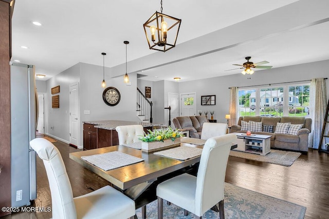 dining room with dark hardwood / wood-style floors and ceiling fan with notable chandelier