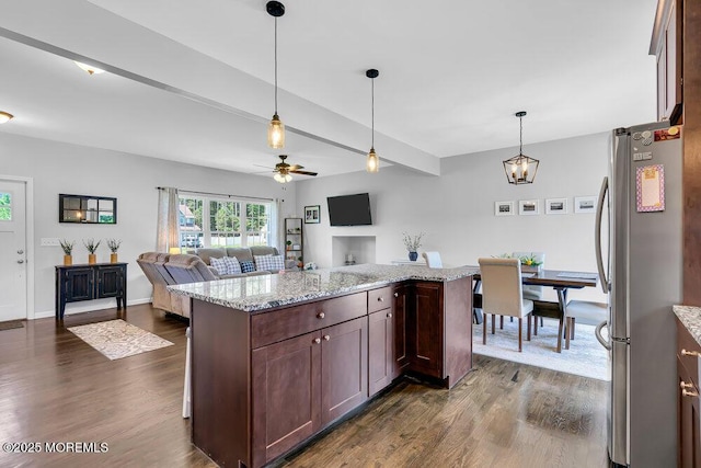 kitchen featuring dark brown cabinetry, dark wood-type flooring, light stone counters, and stainless steel refrigerator