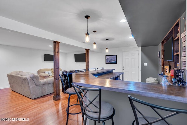 kitchen featuring pendant lighting, a breakfast bar, light hardwood / wood-style floors, and kitchen peninsula