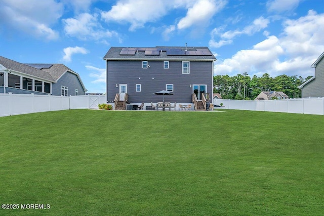 rear view of house with a yard, a patio area, and solar panels