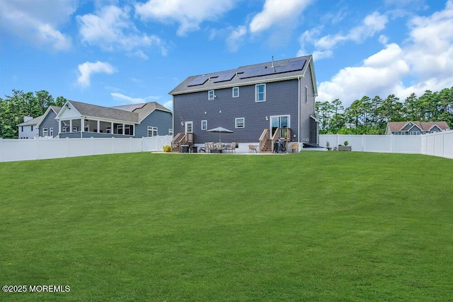 back of property with a yard, a patio area, and solar panels