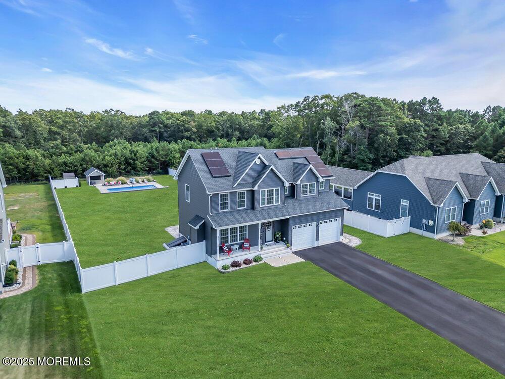 view of front of house featuring a garage, a front yard, solar panels, and covered porch