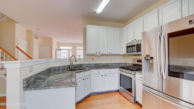 kitchen featuring sink, dark stone counters, white cabinets, and appliances with stainless steel finishes