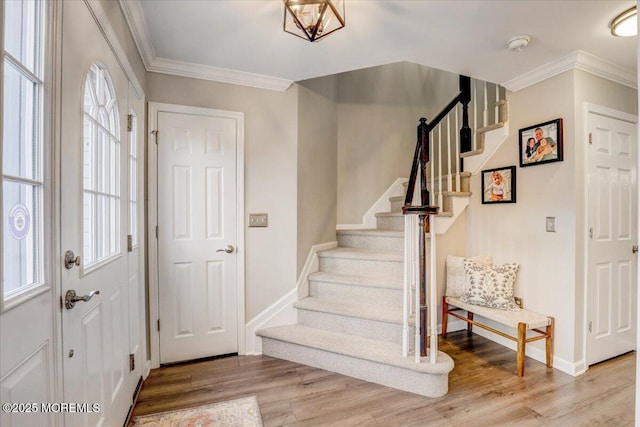 foyer with ornamental molding and light hardwood / wood-style flooring