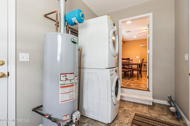 washroom featuring stacked washer / drying machine and water heater