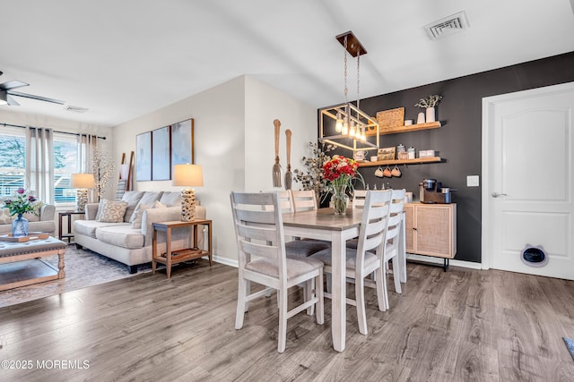 dining space with hardwood / wood-style flooring and ceiling fan with notable chandelier