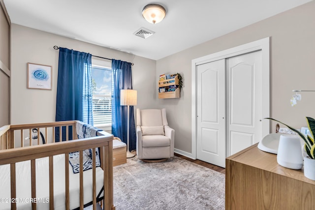 bedroom with hardwood / wood-style flooring, a closet, and a crib