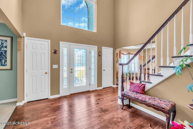 entrance foyer featuring stairs, a high ceiling, baseboards, and wood finished floors