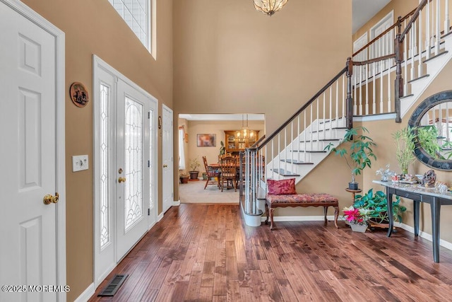 entryway featuring visible vents, a notable chandelier, stairway, and wood finished floors