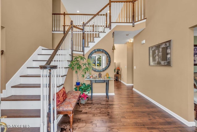 stairs featuring a high ceiling, baseboards, and wood finished floors