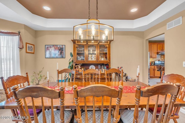 dining space featuring a chandelier, a tray ceiling, visible vents, and recessed lighting