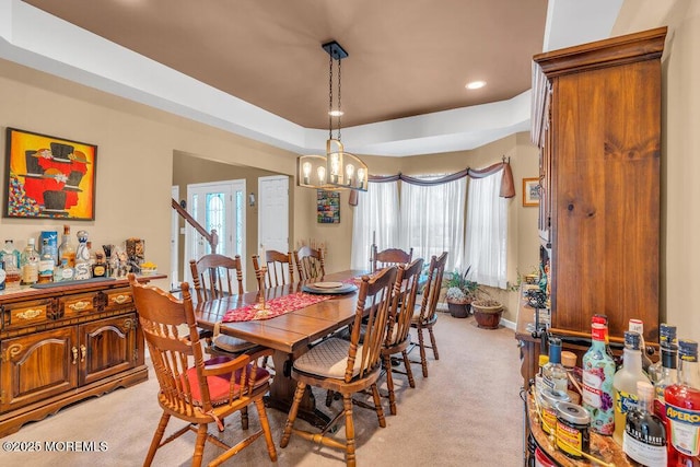 dining area featuring a tray ceiling, recessed lighting, light carpet, a chandelier, and baseboards