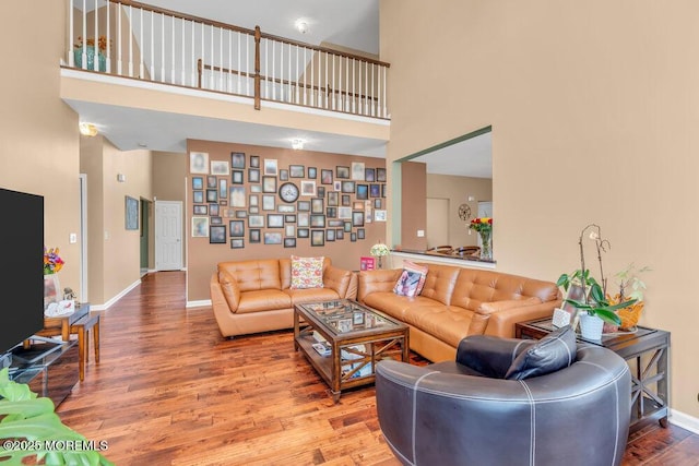 living room with a high ceiling, wood finished floors, and baseboards