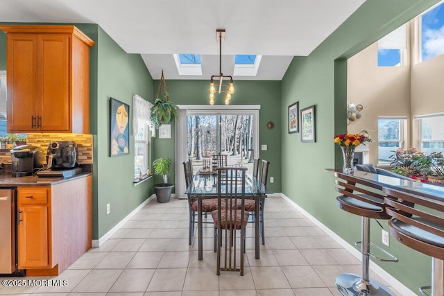 dining space with a skylight, light tile patterned floors, and baseboards