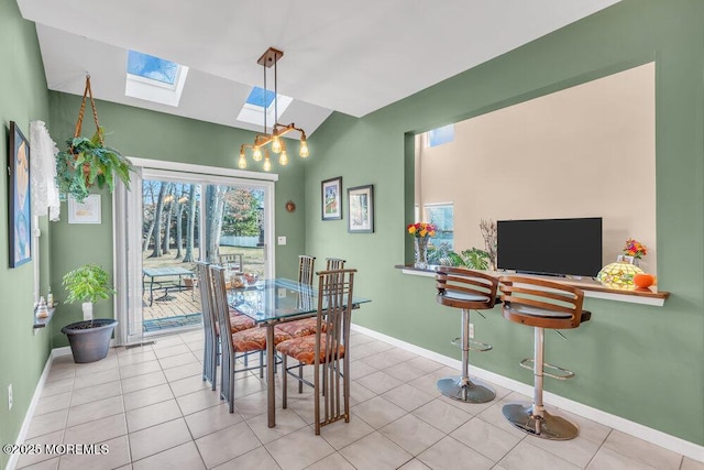 dining area with vaulted ceiling with skylight, baseboards, and light tile patterned flooring