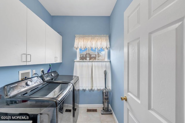 clothes washing area with light tile patterned floors, visible vents, baseboards, washer and dryer, and cabinet space