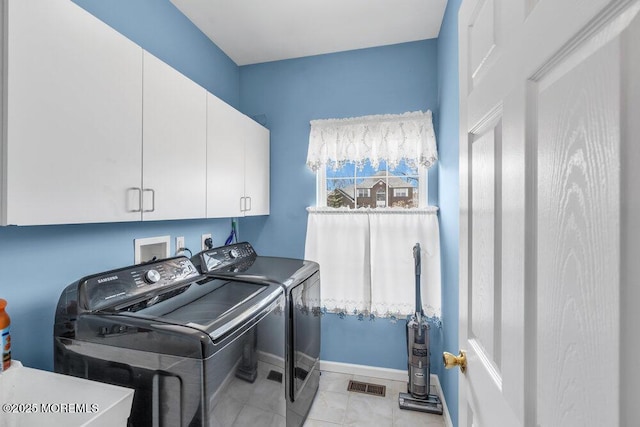 washroom with light tile patterned floors, separate washer and dryer, visible vents, baseboards, and cabinet space