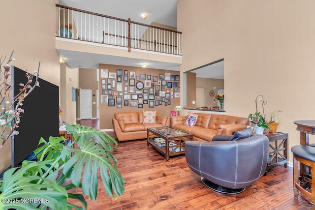 living area featuring a high ceiling, wood finished floors, and baseboards