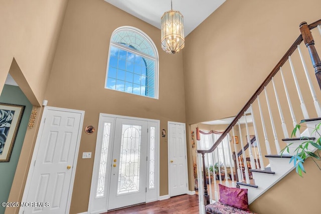 foyer entrance with a high ceiling, stairs, a chandelier, and wood finished floors