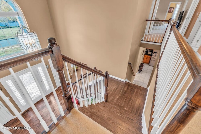 staircase with a high ceiling, baseboards, and wood finished floors