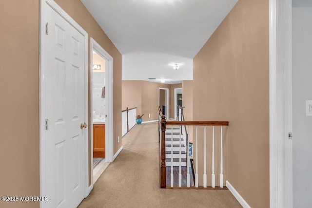 hallway featuring light carpet, an upstairs landing, and baseboards