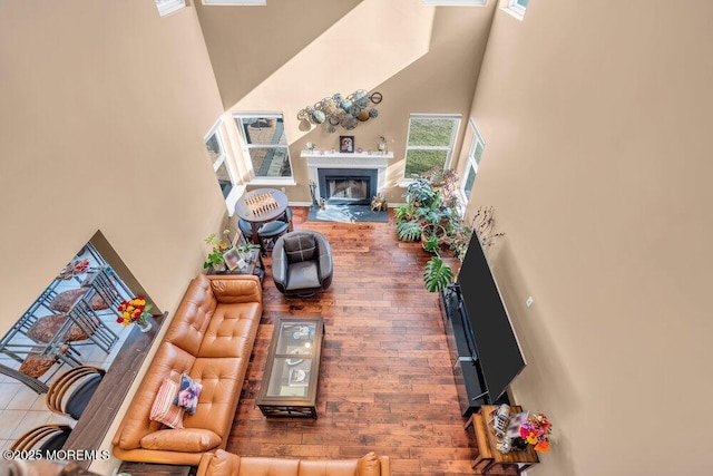 living room featuring a towering ceiling, a fireplace, and baseboards