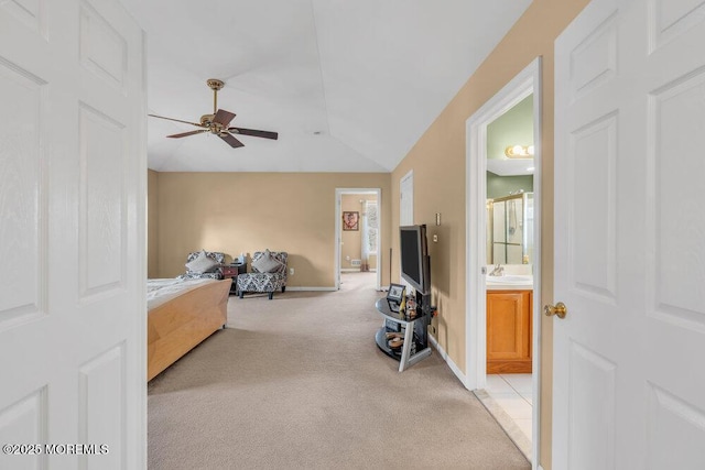 bedroom with light colored carpet, a sink, baseboards, vaulted ceiling, and ensuite bath