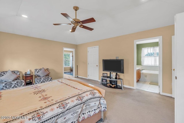 bedroom with lofted ceiling, multiple windows, ensuite bathroom, and light colored carpet