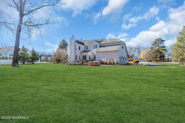 back of property featuring a garage, a chimney, a residential view, and a lawn