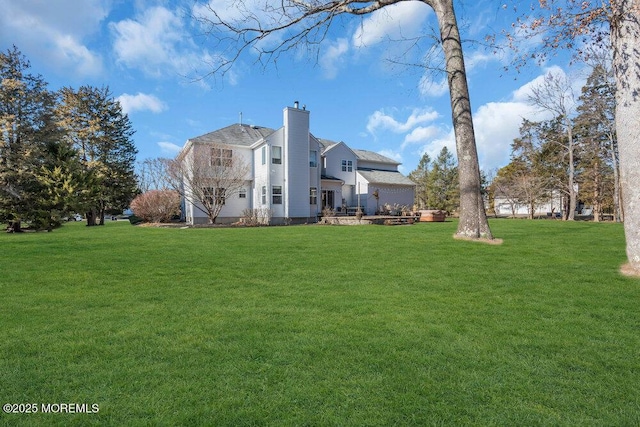 back of house featuring a chimney and a yard