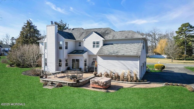 back of property featuring a patio, a lawn, and a chimney