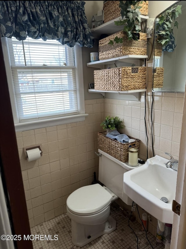 bathroom featuring tile patterned flooring, sink, tile walls, and toilet