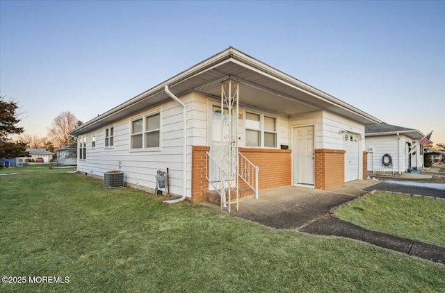 property exterior at dusk featuring a garage, a lawn, and central AC