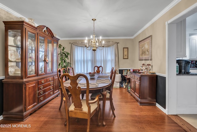 dining space with hardwood / wood-style flooring, crown molding, and a chandelier