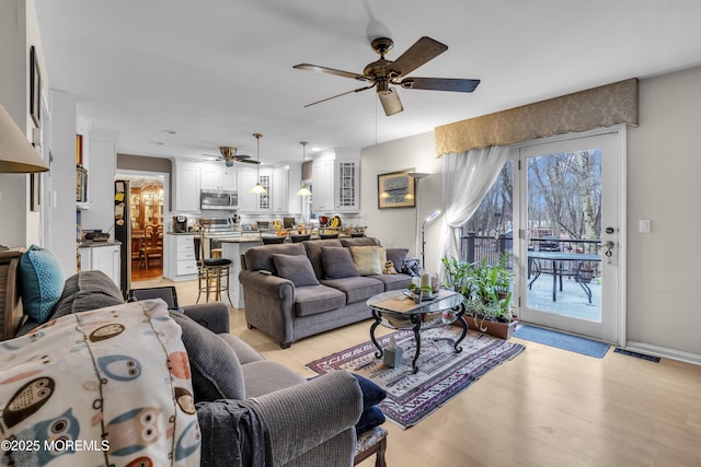 living room with light hardwood / wood-style floors and ceiling fan