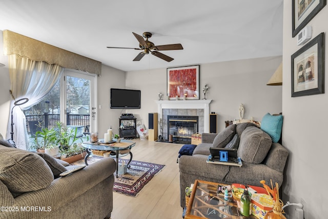 living room featuring ceiling fan, wood-type flooring, and a tile fireplace