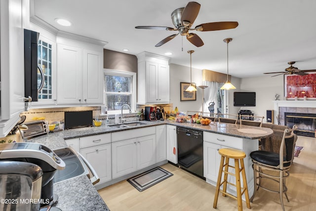 kitchen with pendant lighting, dishwasher, sink, a breakfast bar area, and white cabinets