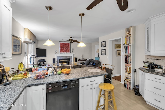 kitchen with white cabinetry, a kitchen breakfast bar, dishwasher, and dark stone countertops