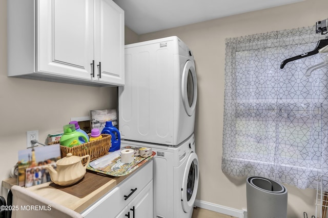 clothes washing area with stacked washer / dryer and cabinets