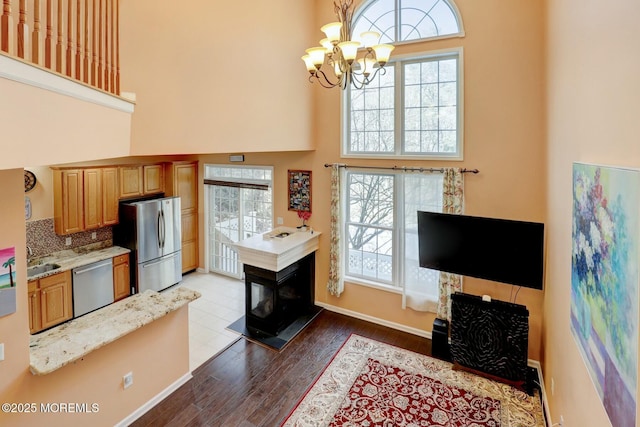 living area featuring a chandelier, plenty of natural light, a high ceiling, and dark wood finished floors