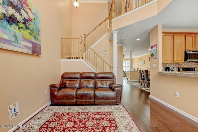 living room with baseboards, wood-type flooring, stairs, and ornate columns